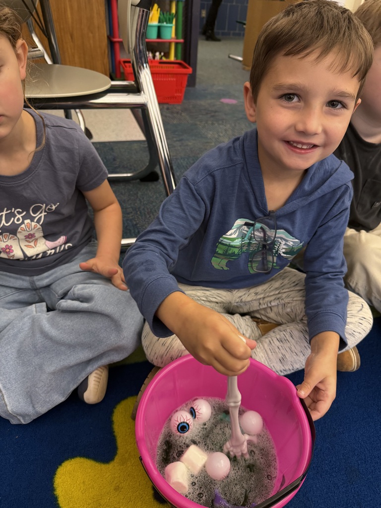 A student stirs his spooky soup while smiling