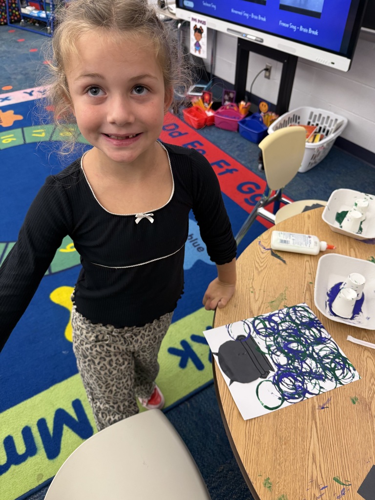 A student smiles while showing the drawing she made of the spooky soup