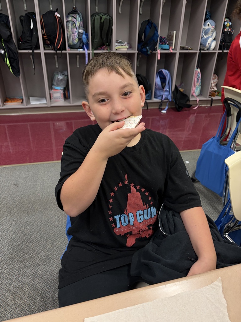 A student smiles while taking a bite of a pop tart