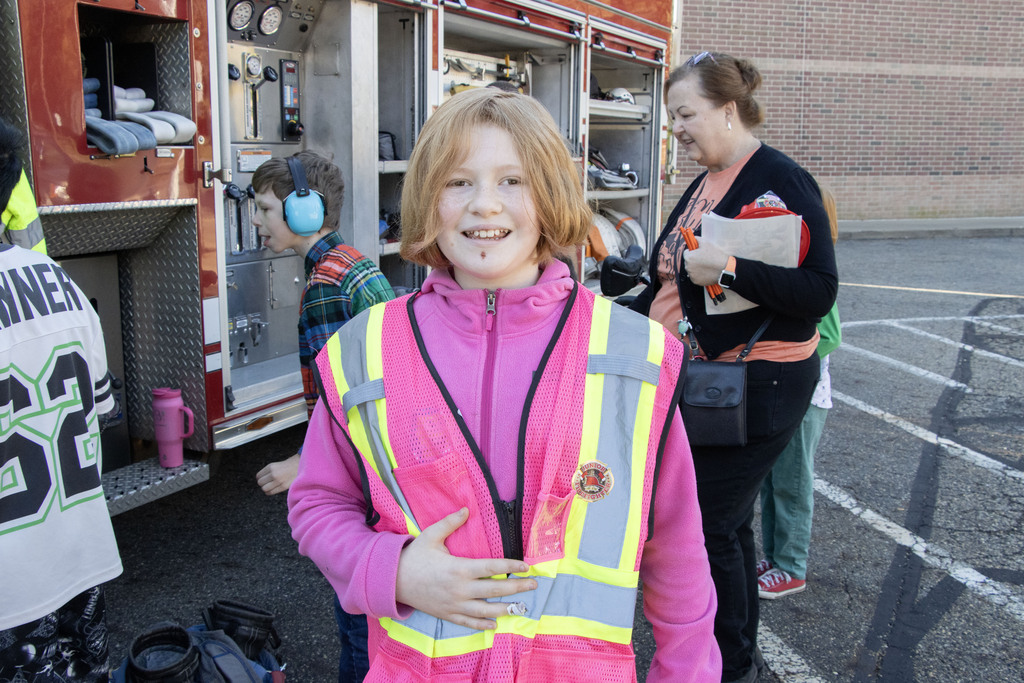 A student wears a pink reflective vest that belongs to a firefighter