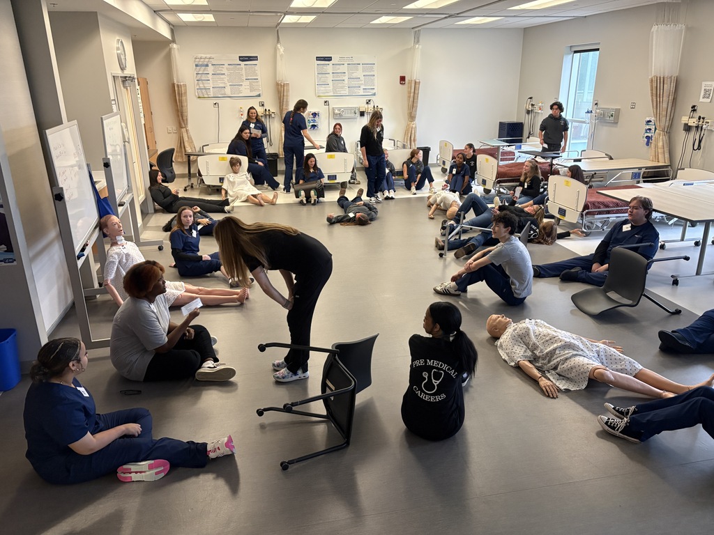 The Pre med student sit on the floor during the simulation while the KSU Stark students lead the simulation