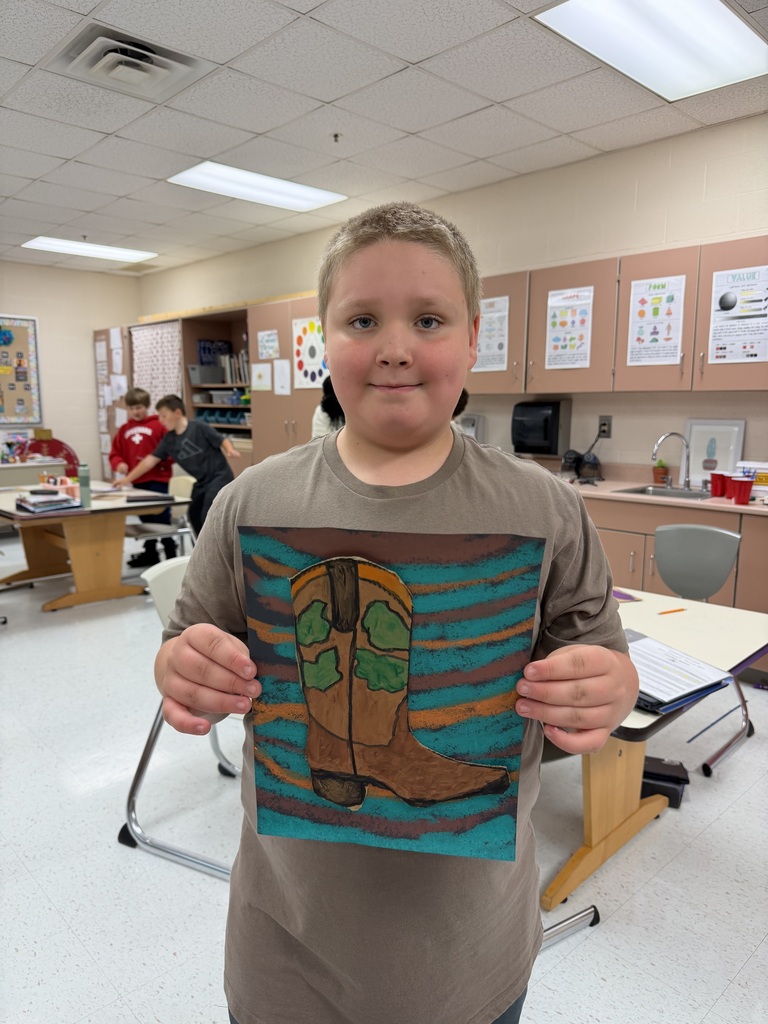 A student holds up the cowboy boot they designed in class