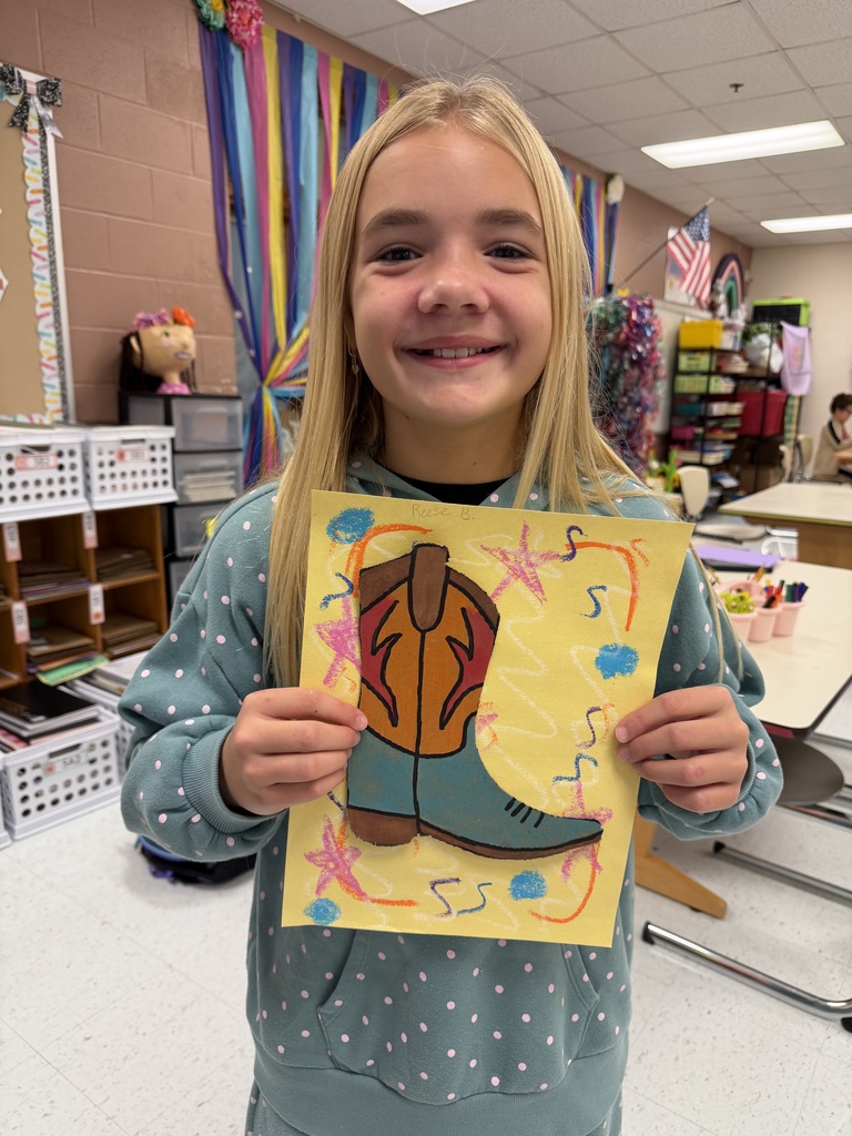 A student holds up the cowboy boot they designed in class