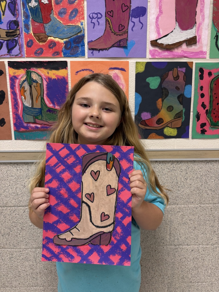 A student holds up the cowboy boot they designed in class