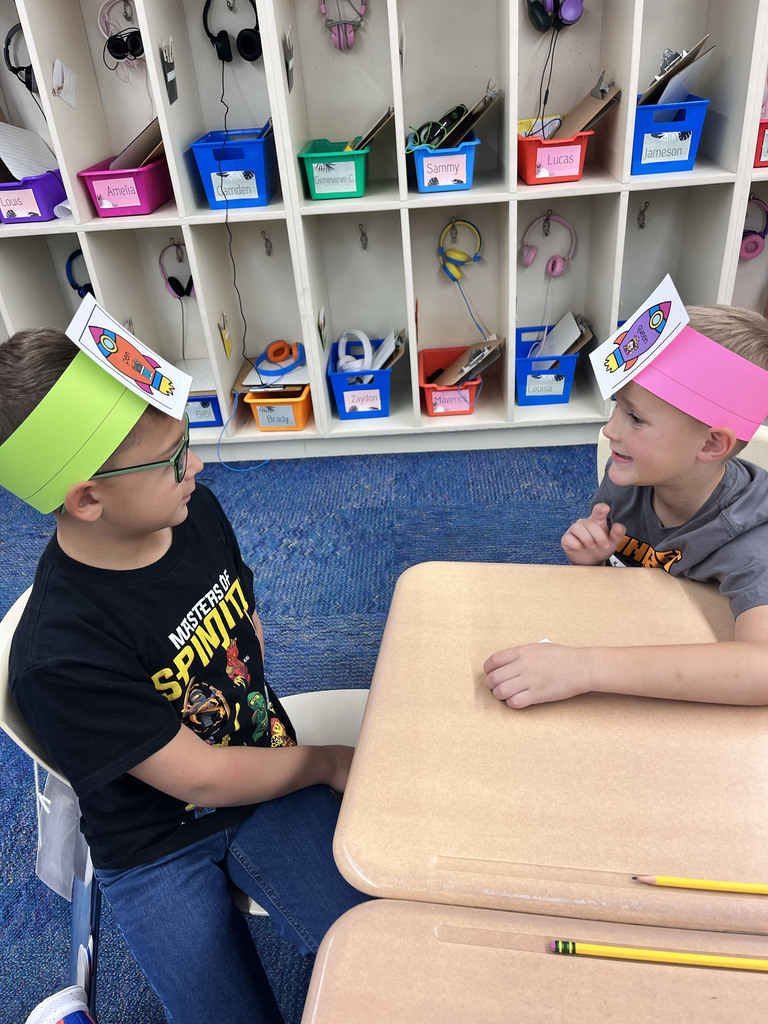 Two students look at each other and guess the nouns on their headbands