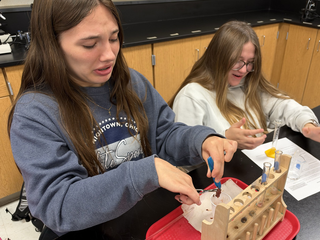 A student takes part in a lab while her partner writes on a piece of paper