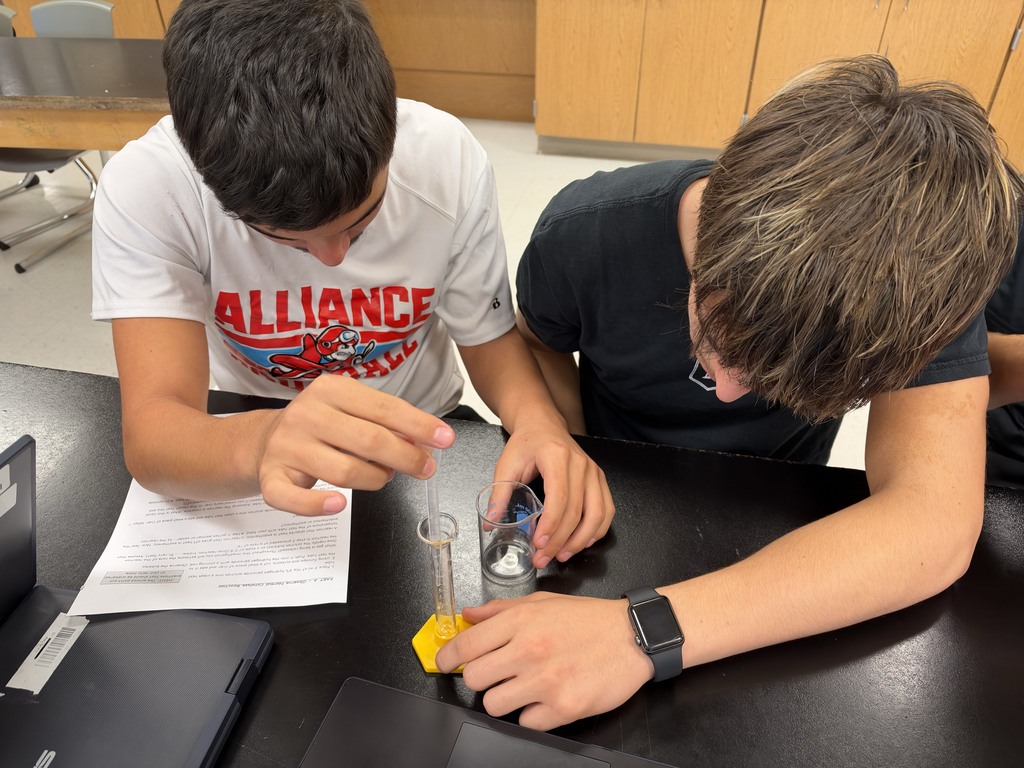 two students add liquid to to a beaker with a pipette