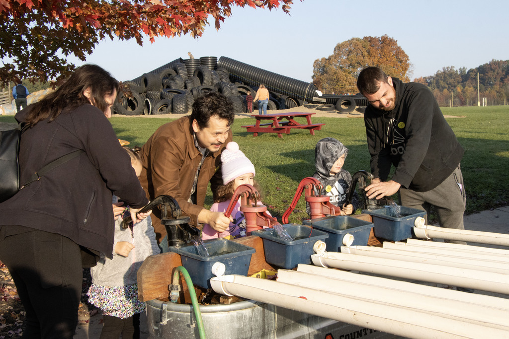 Three students and their parents pump water to move a duck around a small race course