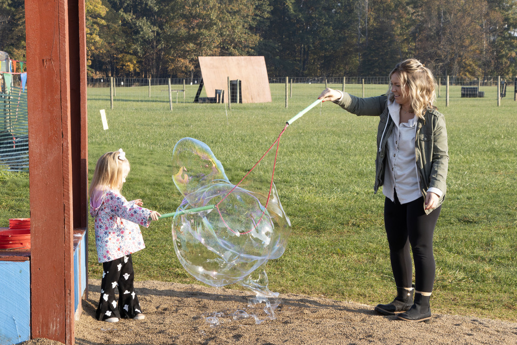 A mother and her daughter use plastic and string to create giant bubbles