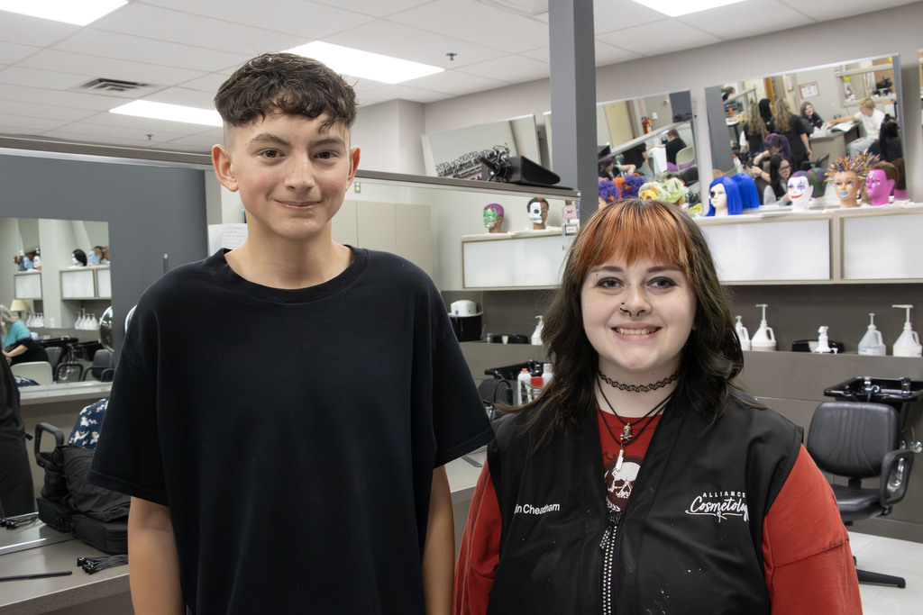 A cosmetology student stands next to a client who's hair she cut