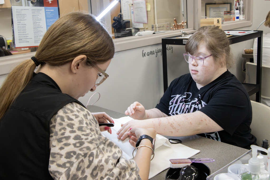 a student extends her arm so a cosmetology student can give her a manicure