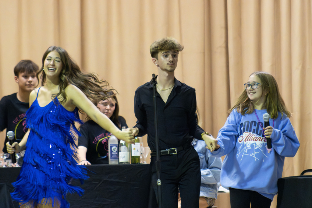 Three students dance on stage