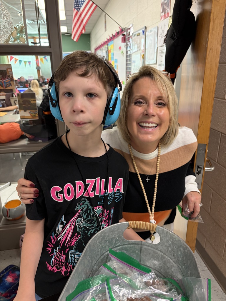 A staff members smiles for a picture with the students who is passing out candy