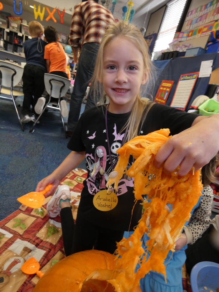 A student holds up a handful of the pumpkins insides