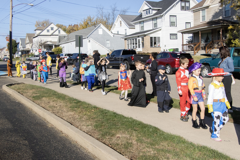 a group of students dressed in costume walk along the side walk