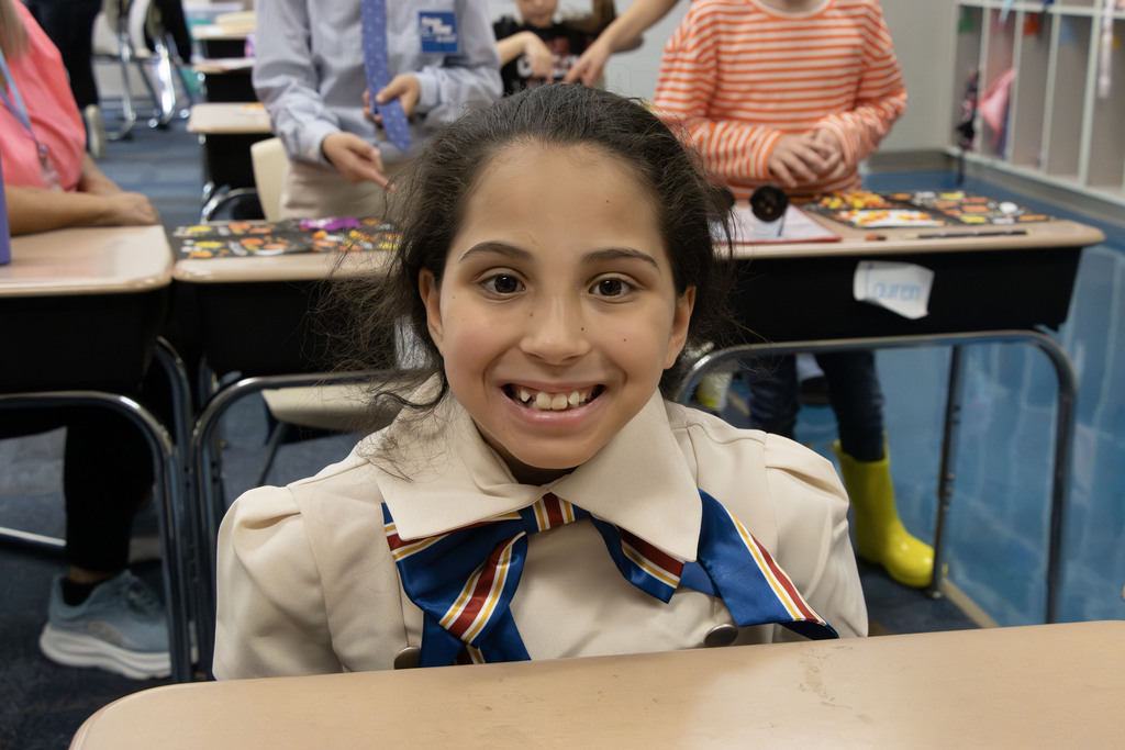 A student dressed as a flight attendant sits at her desk