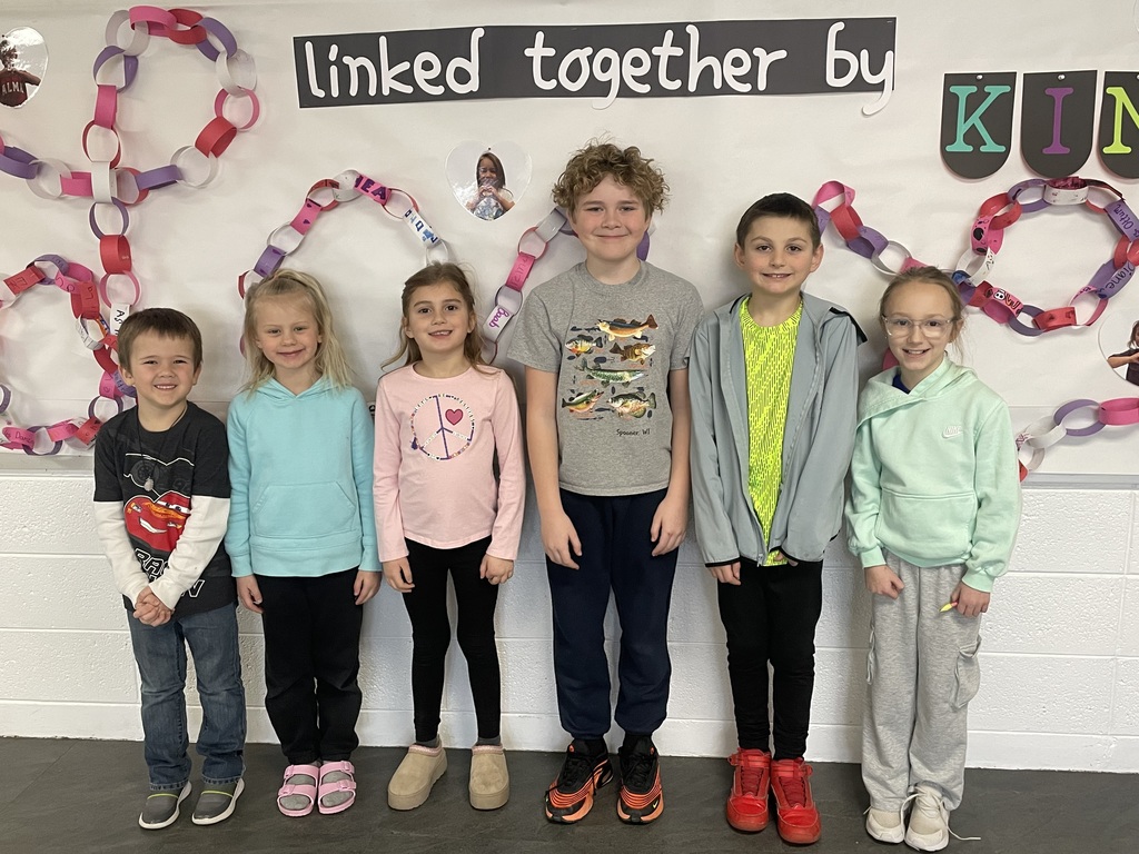 Six children stand smiling in front of a school wall decorated with colorful paper chains and a sign about kindness. The students include: Grayson Hoch, Ruby Reidt, Piper Curtis, Austin Ritscher, Fletcher Henderson, and Shae Ressie. 