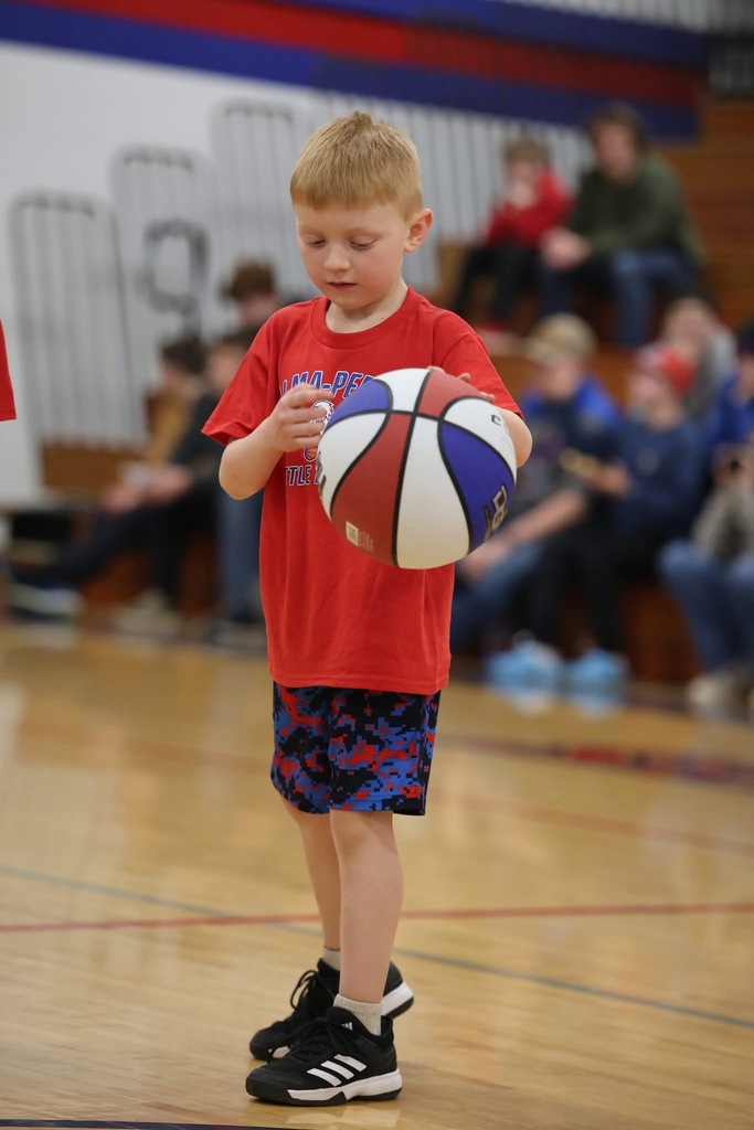 A young boy is looking down at the ball, focusing on the mechanics of his dribble and hand placement.