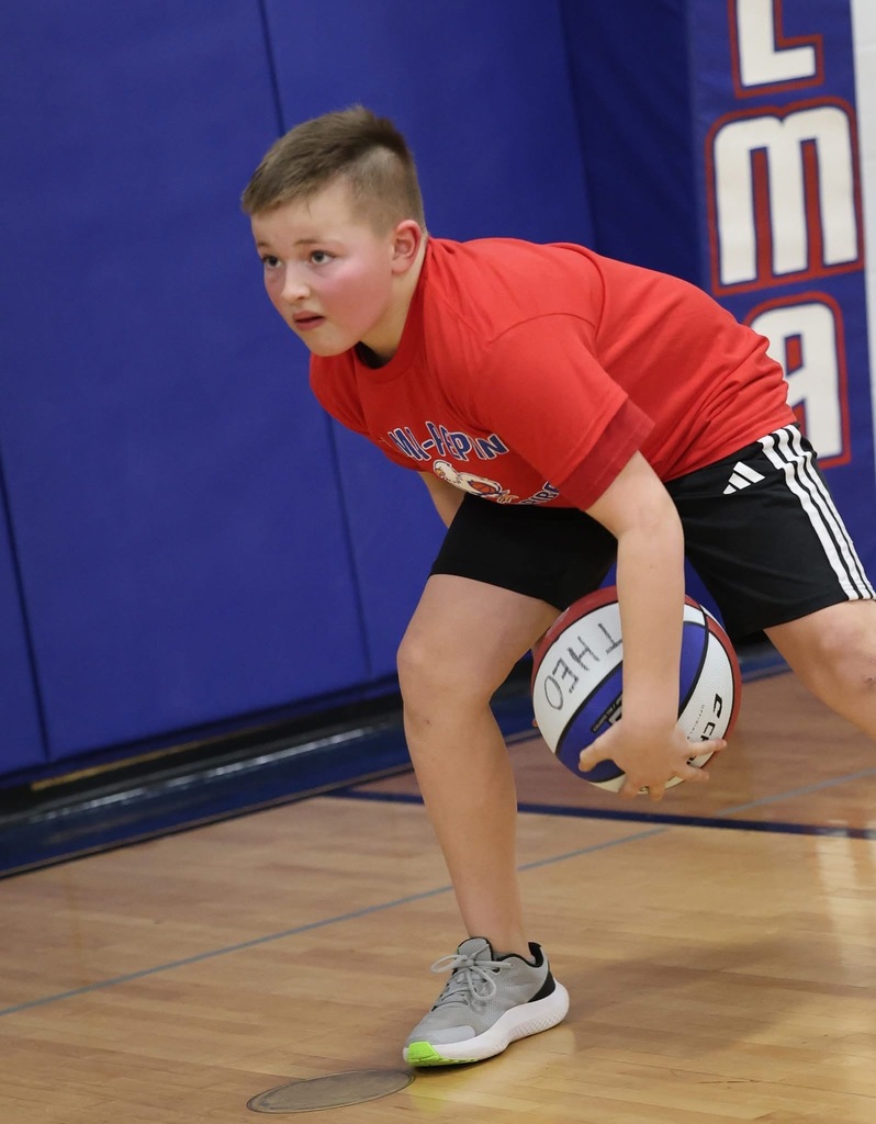 A boy named "Theo" (name written on the ball) is shown in a low, athletic crouch, practicing a controlled dribble near the sideline.