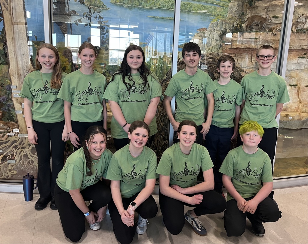 This photo shows Alma and Pepin 7th Grade students dressed in a green t shirt standing in front of a nature scene.  