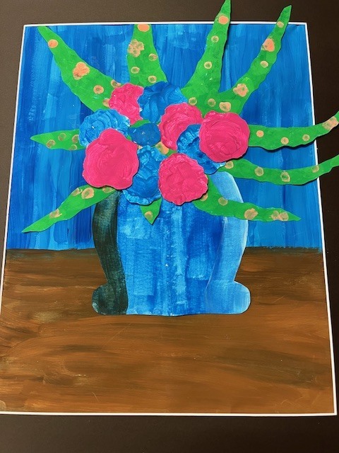 A vibrant mixed-media collage of a flower bouquet. It features pink and blue painted paper flowers with long, green, polka-dotted leaves bursting out of a blue vase. The background is a textured blue sky over a brown surface.