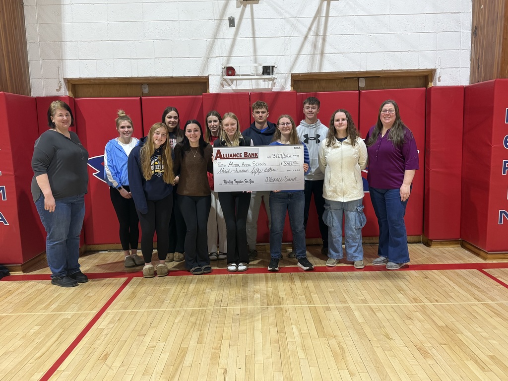 Alma's National Honor Society Members, standing in front of red mats, and holding a $350 check from the Alliance Bank