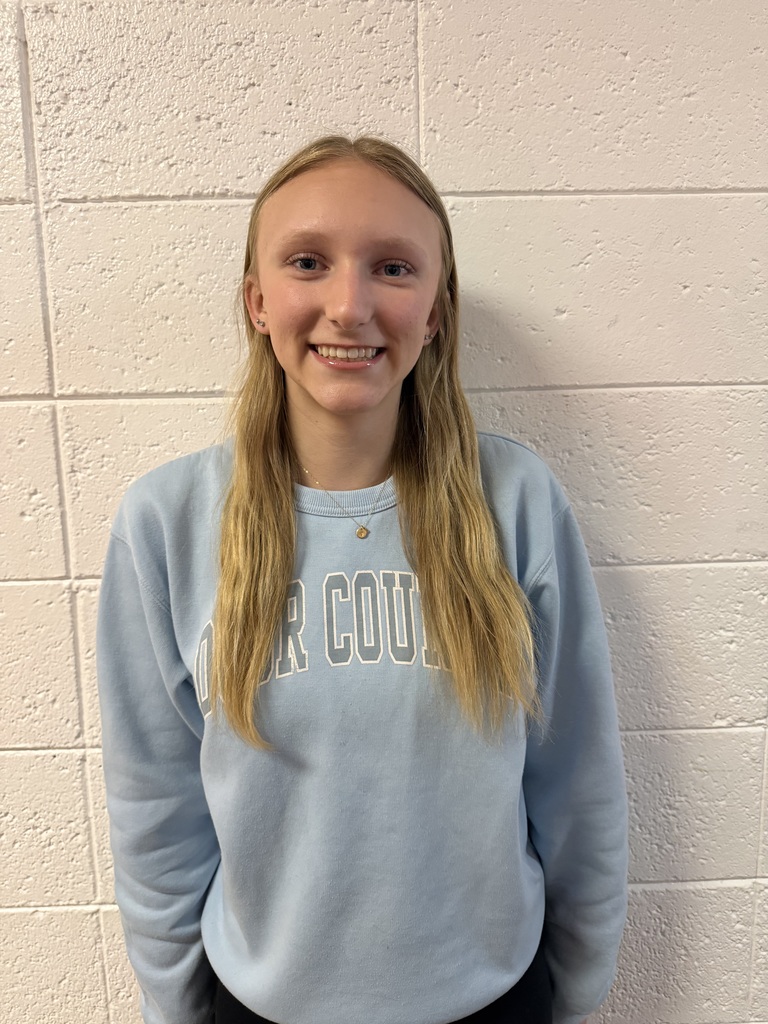 Picture of student standing against a white brick wall.
