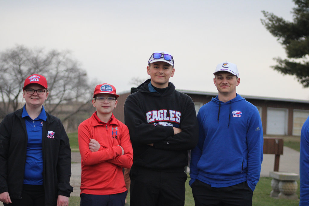 Four Eagle golfers: Lizzy Graner, Hunter Schmalzridt, Holten Fernholz, and Trenton Krzoska smiling at the camera before a golf meet. 