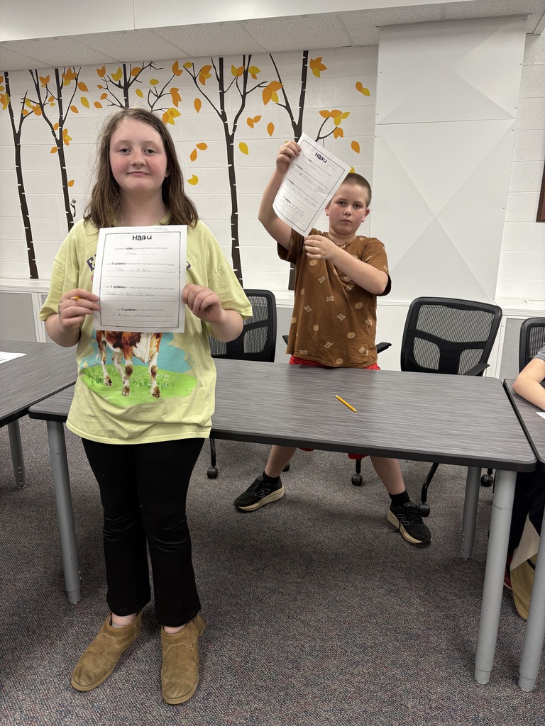 A photo of two 5th graders holding up there poetry they had written.