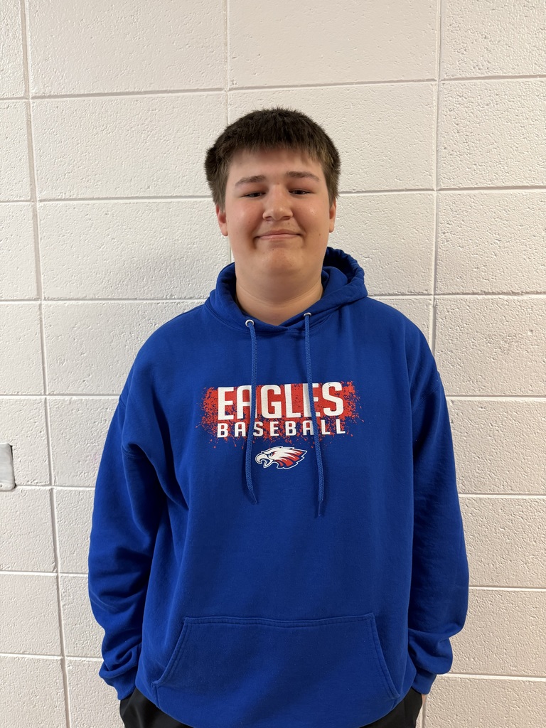 Riley weaver standing and smiling against the wall.