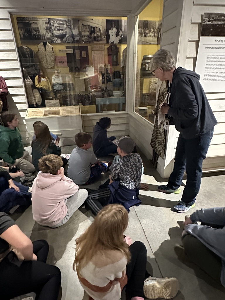 A group of 4th graders looking into a  museum case. 