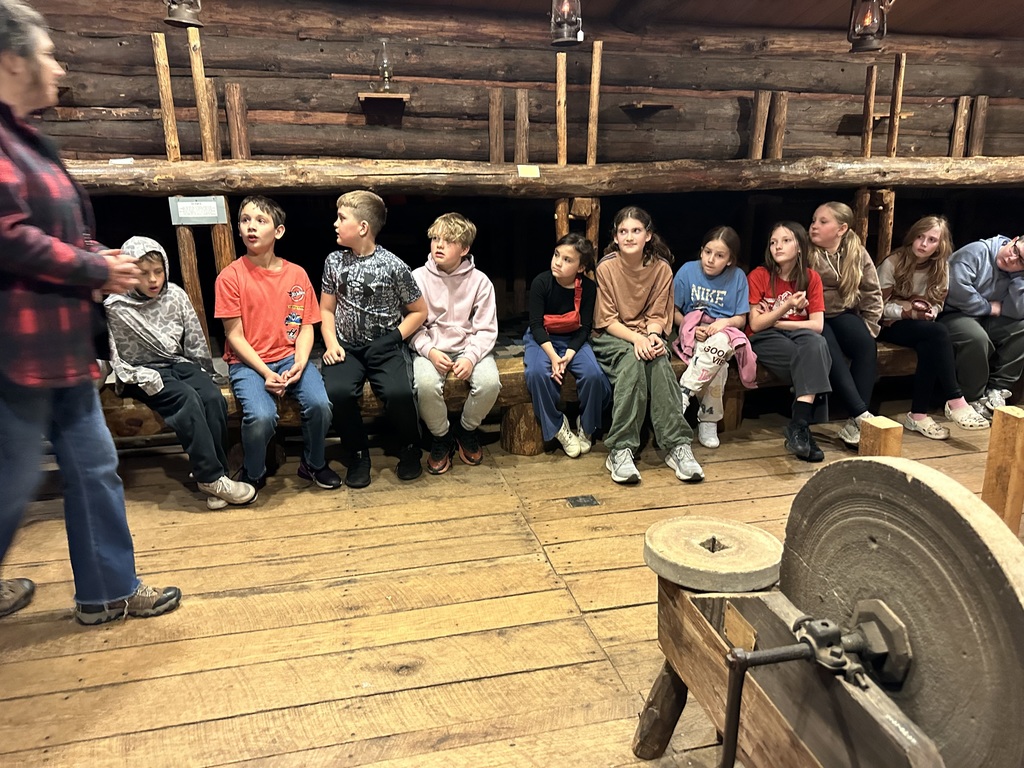 The fourth Graders sitting on the bunk beds listening to the tour guide. 