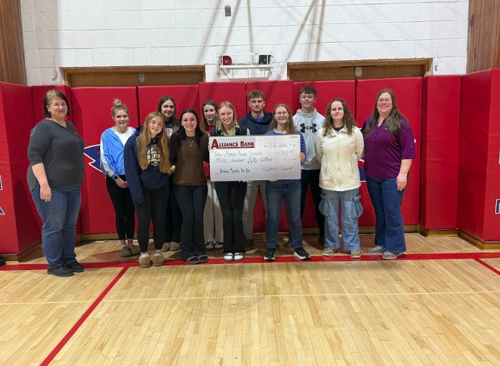 Students and members of Alliance Bank smiling and holding a check.