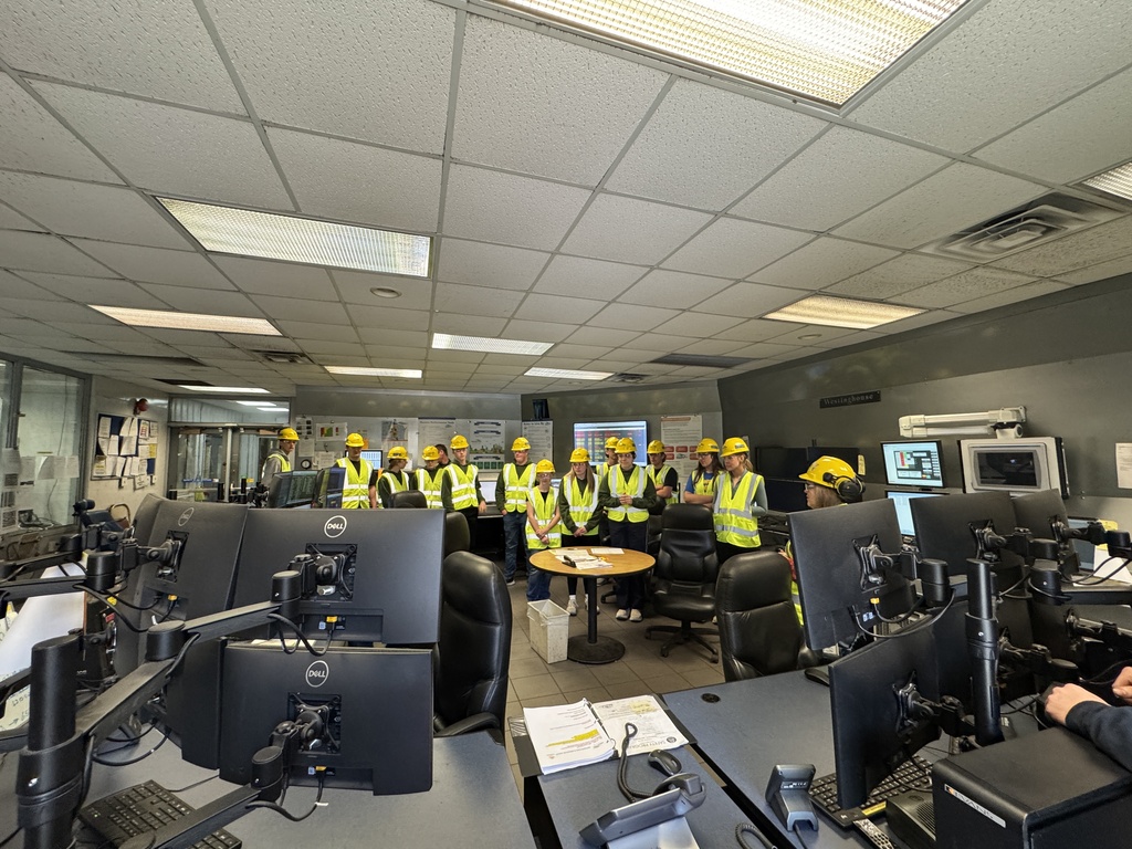 Riverland Amabassadors smiling at the camera inside the control room at the JPM power plant. 
