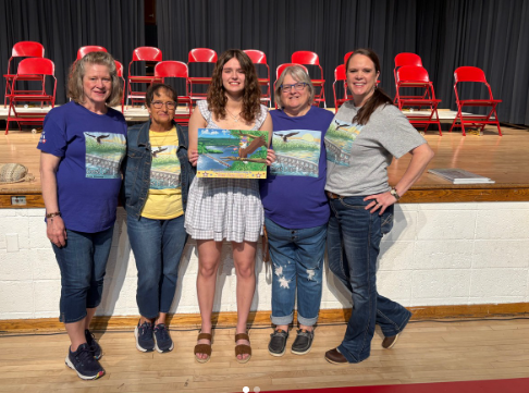 Alma Chamber of Commerce standing and smiling with winning artist, Isabella Olson.