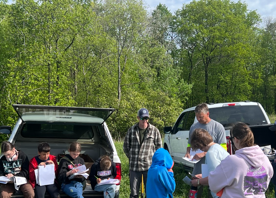 Kids listening to two guys speak. 