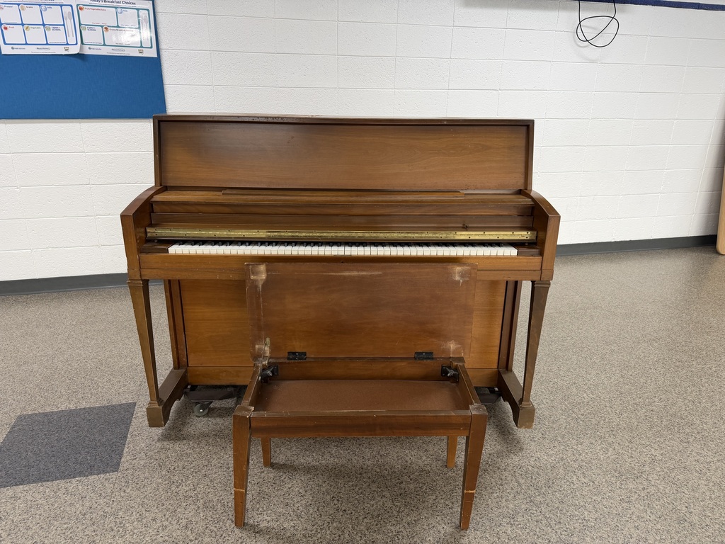 piano with the cover up to see the keys and the bench seat up to see the storage there. Normal size piano made of wood.