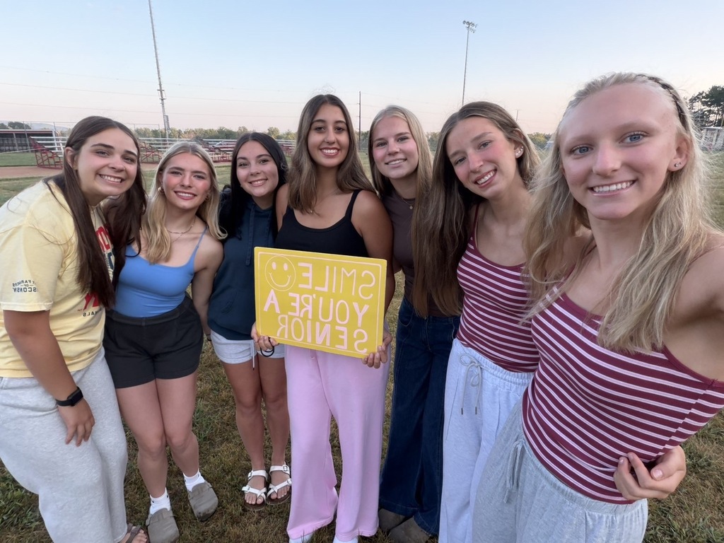 Girls smiling  and holding a sign that says, "Smile You're A Senior". 