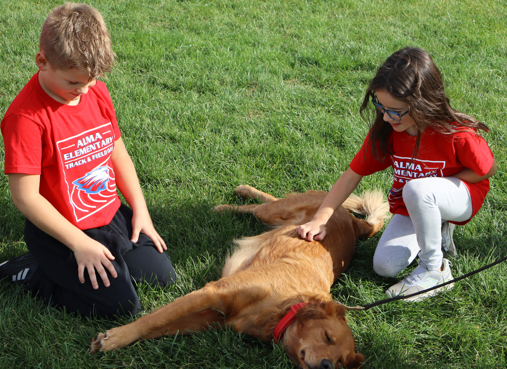 Two students petting a golden retriever.