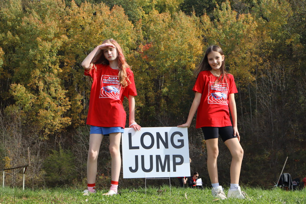 Two girls standing front of a sign that says "long jump".