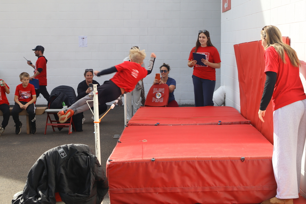 A boy mid jump, ready to land on a thick red mat.