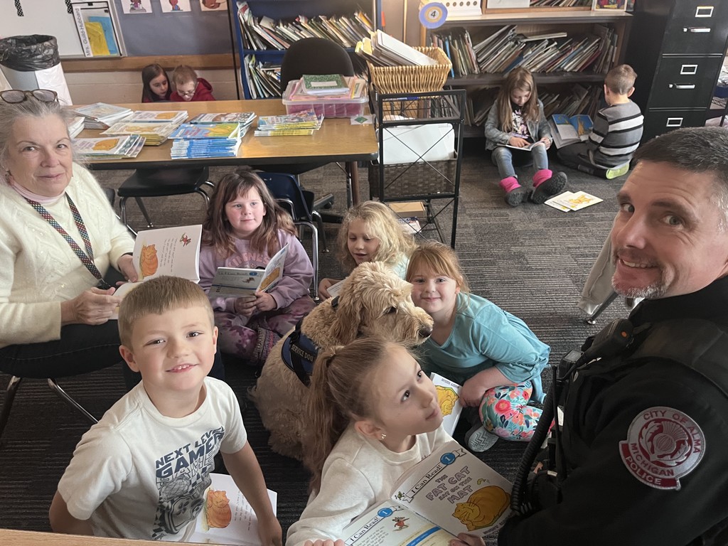 Officer Mueller and Blue listen to students read.
