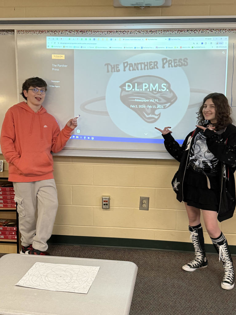 2 middle school newspaper students pose in front of The Panther Press logo on screen