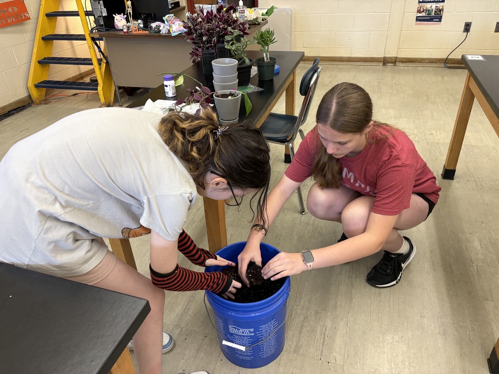 CTE summer camp middle school students getting soil from a bucket to repot plants