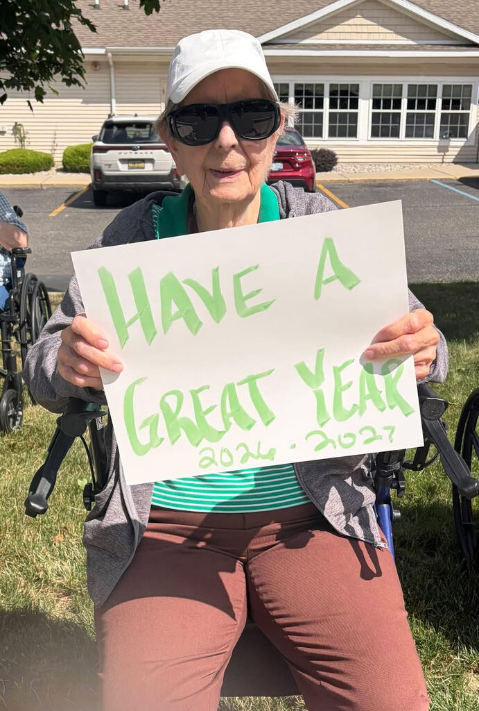 Arbor Grove resident holds white sign with green lettering that says "Have a great year, 2026-2027")