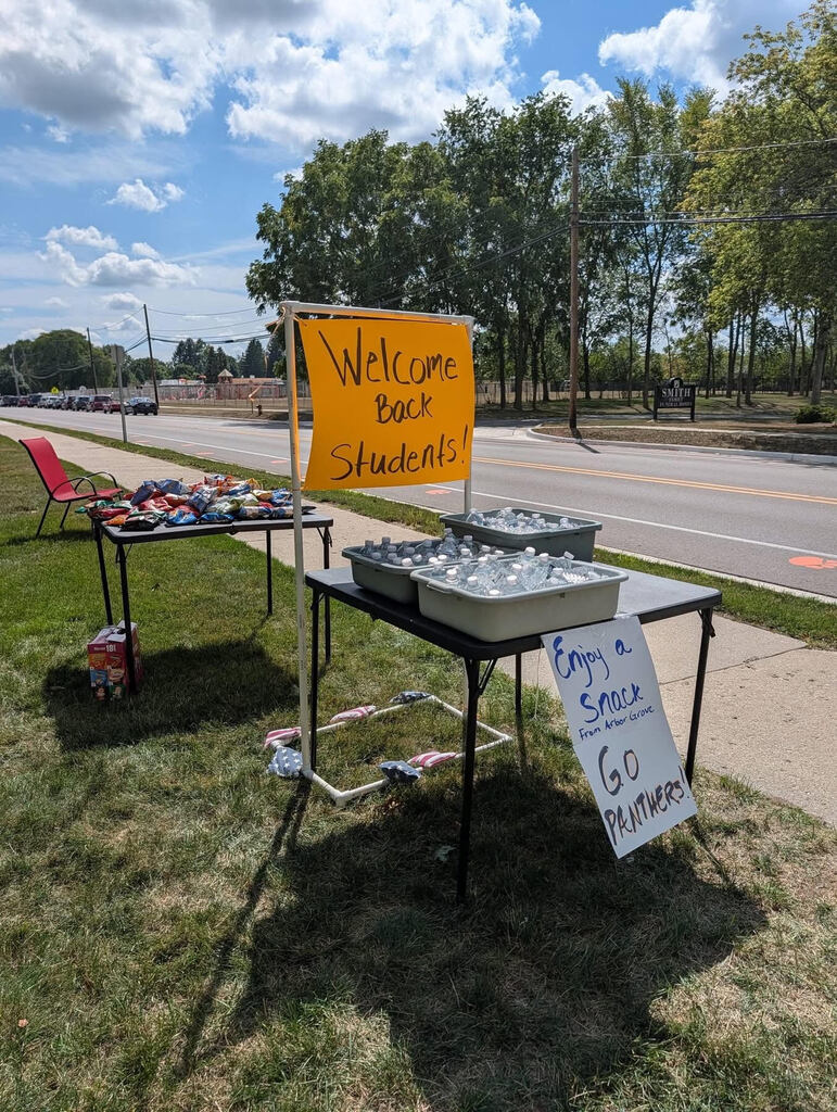 Neon orange "Welcome back, students!" sign on tables on water and snacks
