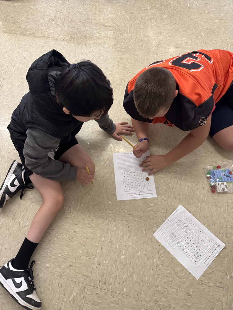Two 5th graders looking at a math worksheet together
