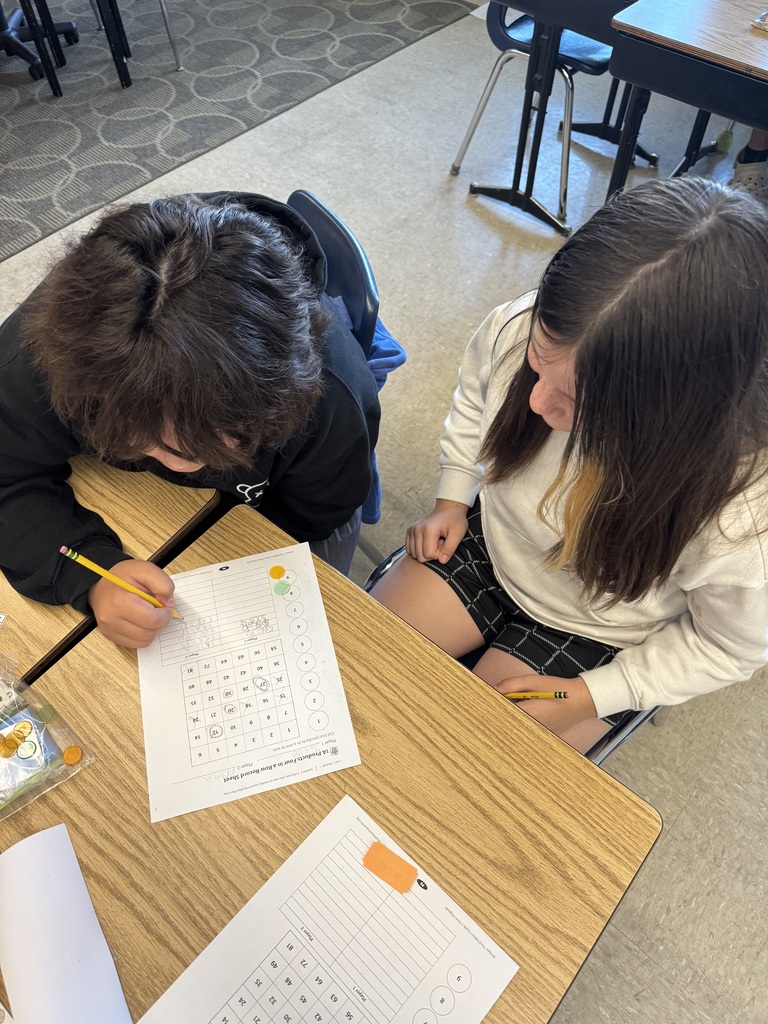 Two 5th graders looking at a math worksheet together