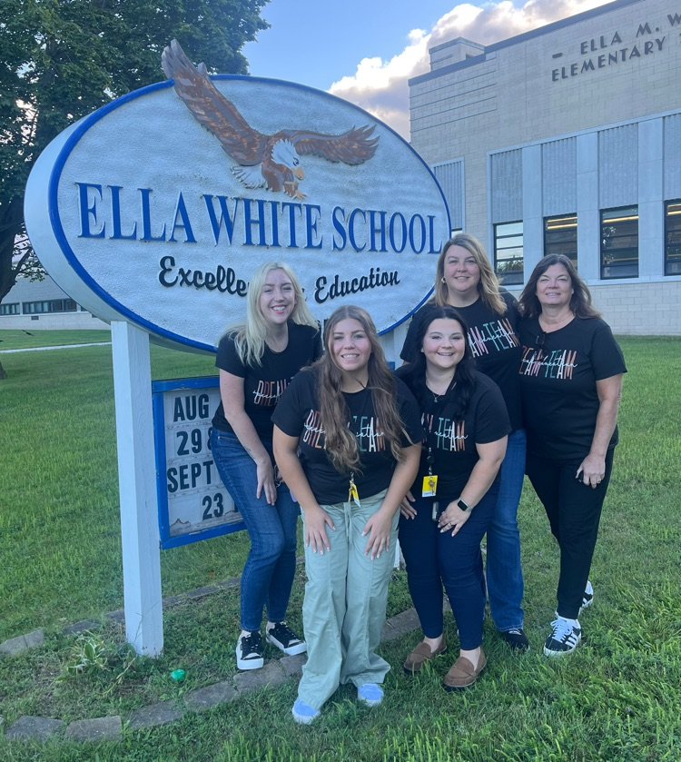 staff smiling by Ella white elementary sign