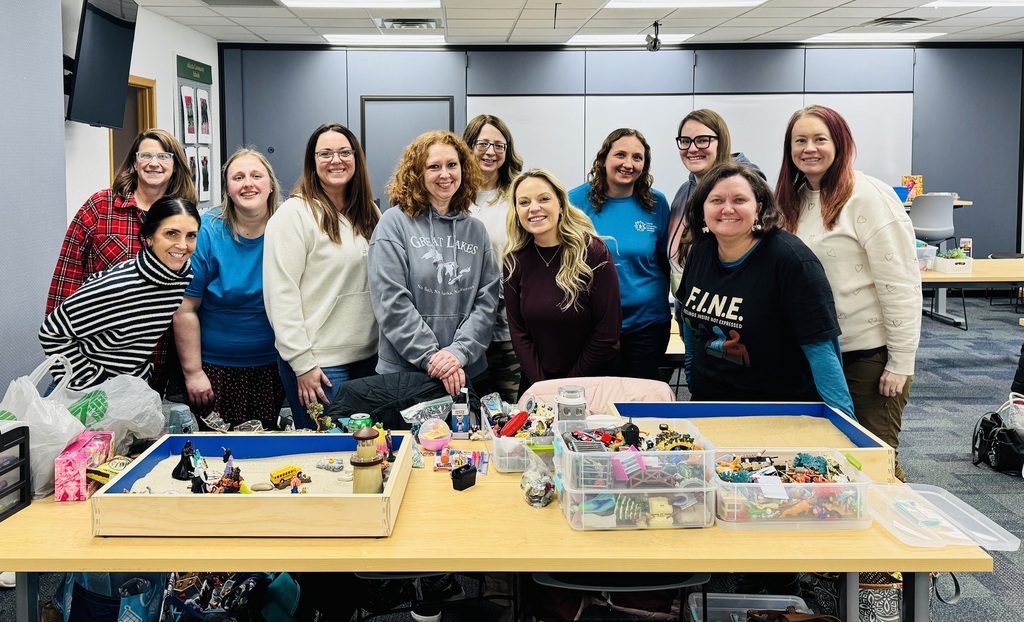 Training participants standing by sandtray supplies.